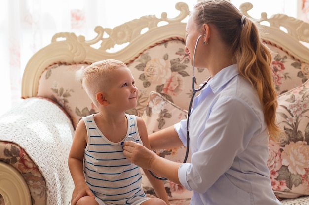 Smiling doctor listening heartbeat of little boy