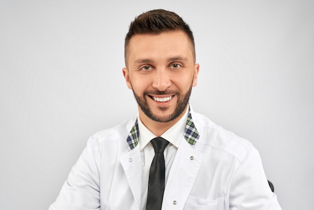 Free photo smiling doctor sitting isolated on grey