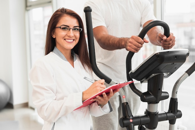 Smiling doctor sitting next to patient working out