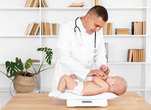 Free photo smiling doctor weighing little baby