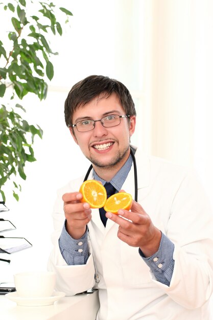 Smiling doctor with orange in hands