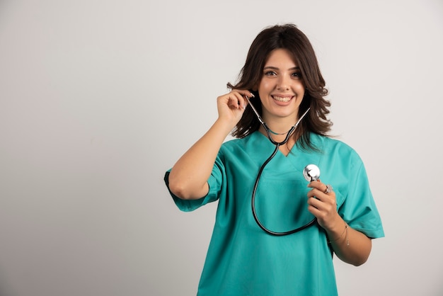Smiling doctor with stethoscope posing on white.