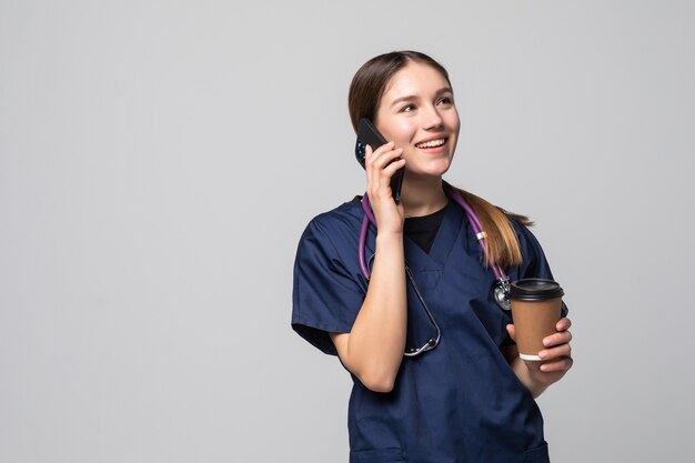 白で隔離の携帯電話を話している医者の女性の笑顔