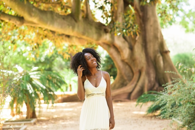 Smiling dreamy black woman walking in park