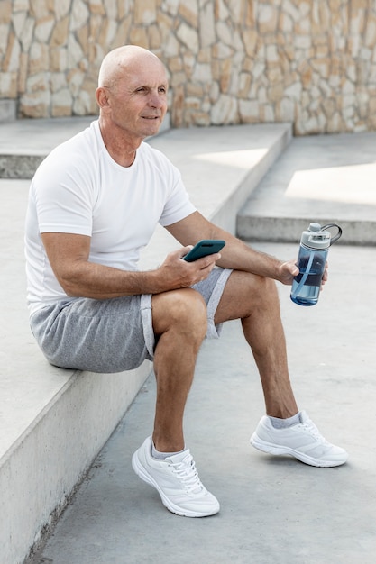 Smiling elder man resting holding his phone