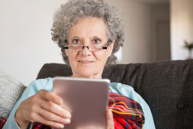 Smiling elderly woman in glasses reading internet news