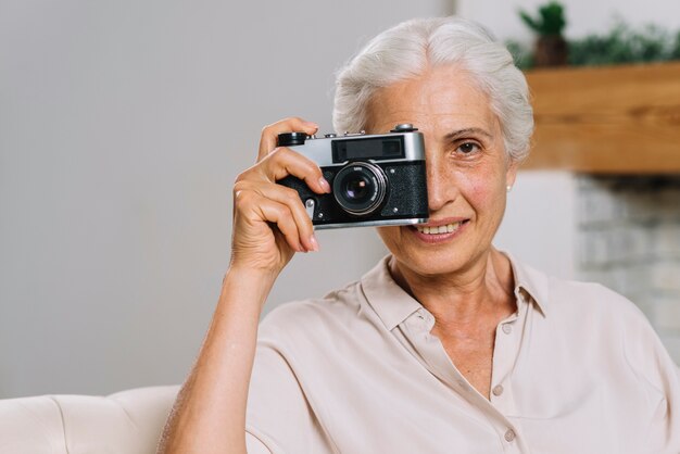 Smiling elderly woman taking photograph from camera