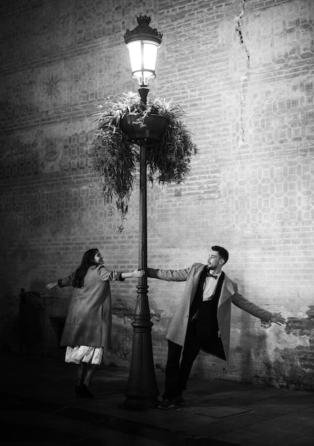 Улыбаясь элегантная женщина и молодой человек кружится возле освещенной уличный фонарь