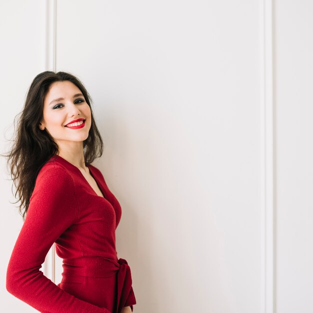 Smiling elegant young woman in red dress in room