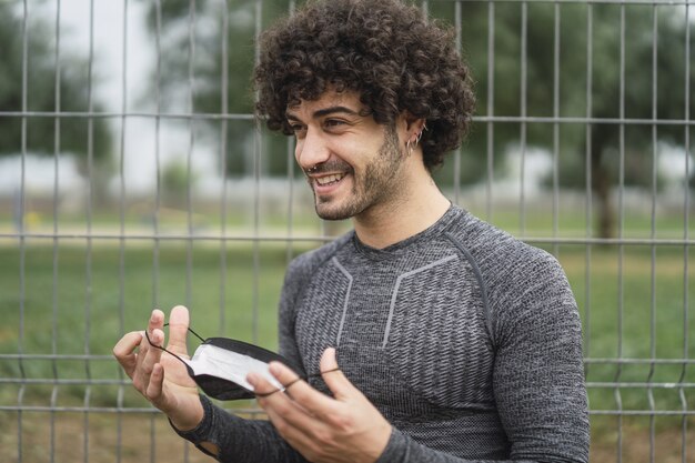 Smiling energetic Spanish guy is about to put on a protective mask