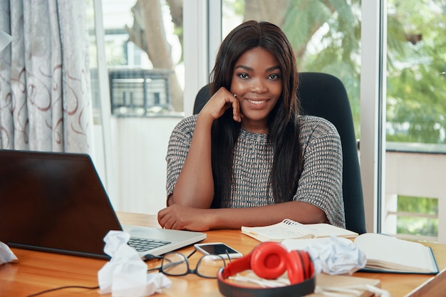 Smiling ethnic businesswoman at working table