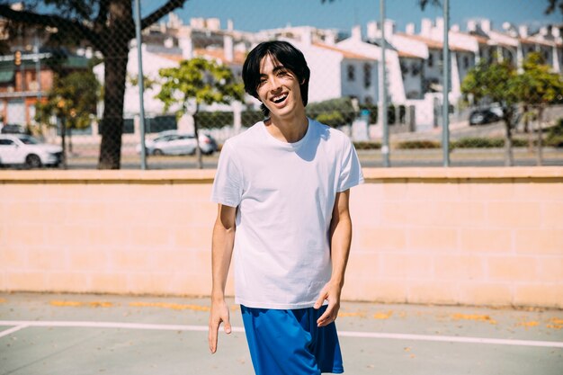 Free photo smiling ethnic male in sportswear standing on playground