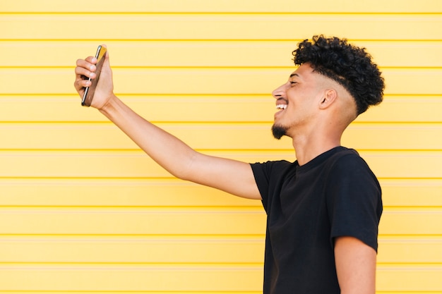 Sorridente uomo etnico prendendo selfie