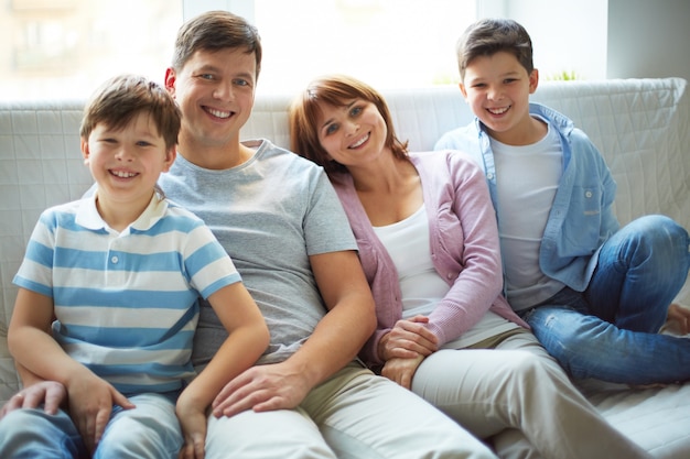 Smiling family sitting on white sofa