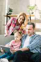 Foto gratuita famiglia sorridente che per mezzo insieme della compressa digitale a casa