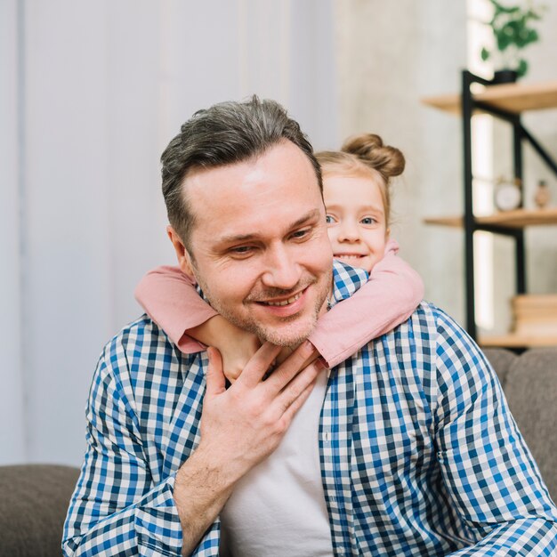 Smiling father carrying his daughter on piggyback