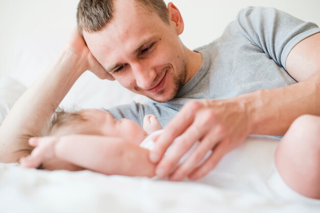 Улыбающийся отец лежал с ребенком на одеяле