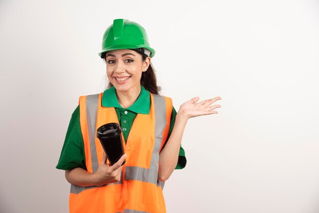 Smiling female constructor with black cup. High quality photo