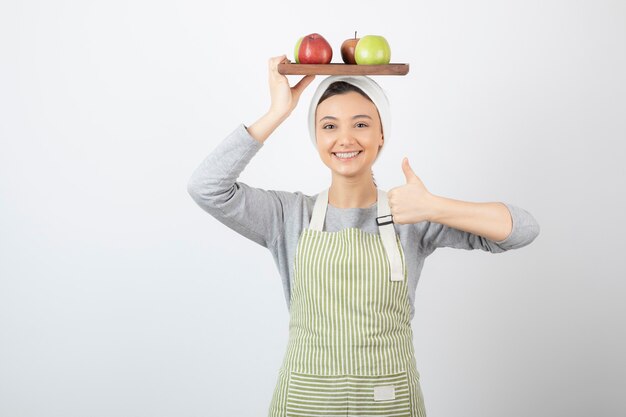 smiling female cook holding plate of apples on white.