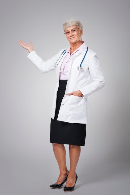 복사 공간에서 가리키는 웃는 여성 의사
