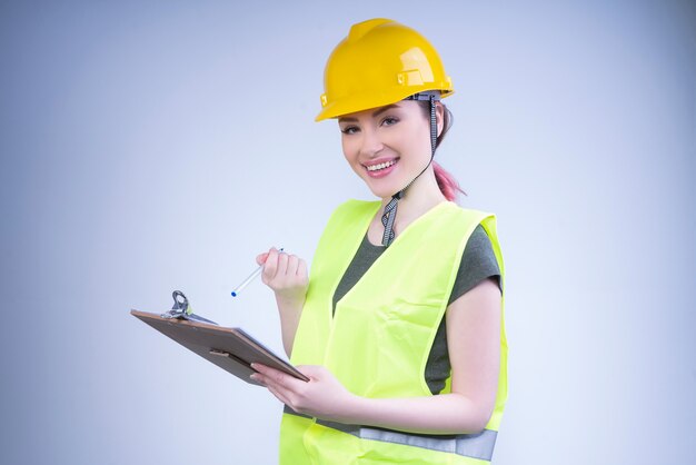 Smiling female engineer in a yellow helmet makes notes