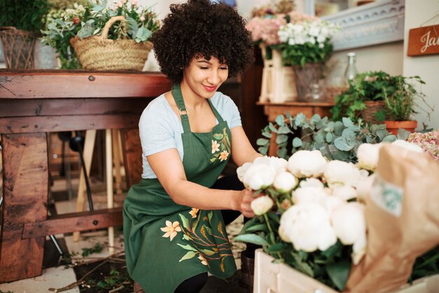 Smiling female florist arranging white peony flowers