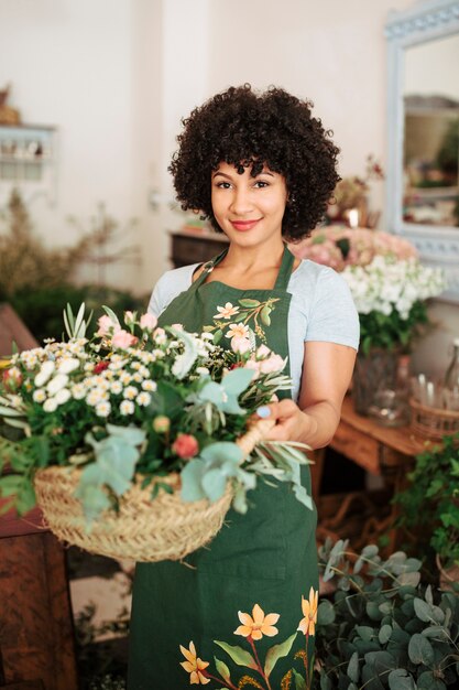 Smiling female florist holding basket of flowers