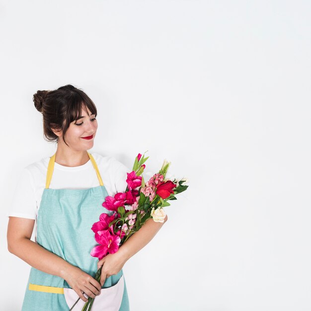 Smiling female florist with bunch of flowers standing on white background