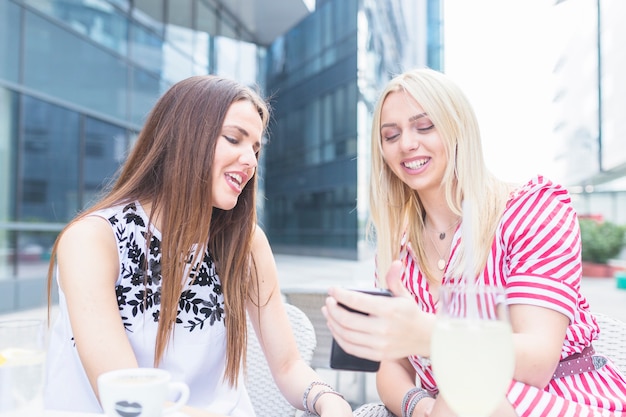 Smiling female friends looking at mobile phone