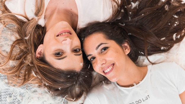 Smiling female friends lying on feathers