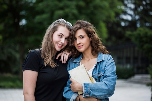 Smiling female friends with books in park