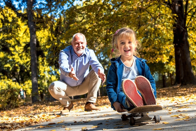 Smiling female grandchild playing with her grandfather in the park