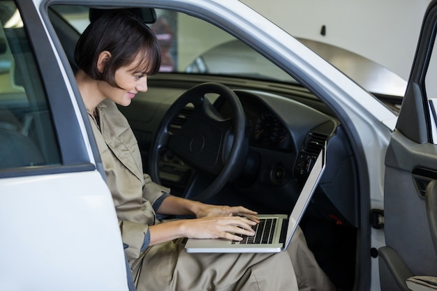 Smiling female mechanic using laptop