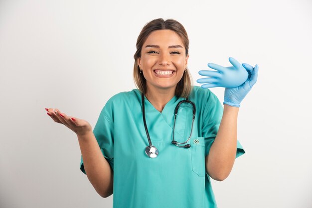 Smiling female nurse wearing latex gloves on white background.