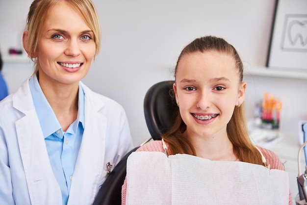 Foto gratuita sorridente ortodontista femminile e bambino nell'ufficio del dentista