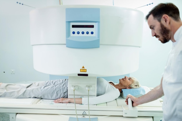 병원에서 방사선 전문의의 감독하에 복부 MRI 스캔을 받고 웃는 여성 환자