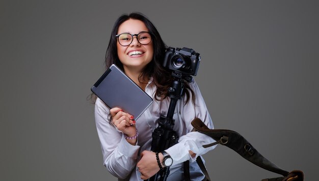 Smiling female photographer holds tripod and tablet PC.
