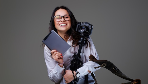 Smiling female photographer holds tripod and tablet PC.