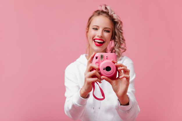 ピンクの壁に取り組んでいる笑顔の女性写真家