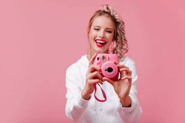 Smiling female photographer working on pink wall