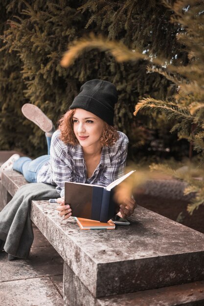 Smiling female in plaid shirt on stone bench