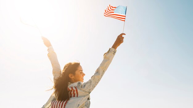 Smiling female raising hands with USA flag