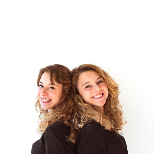 Smiling female standing back to back against white background