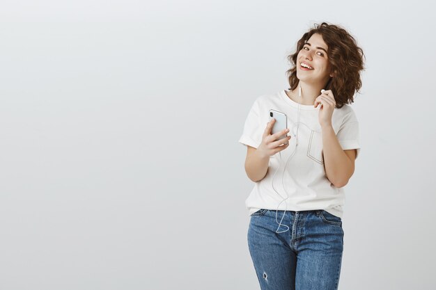 Smiling female student take-off earphone and looking questioned, listen music