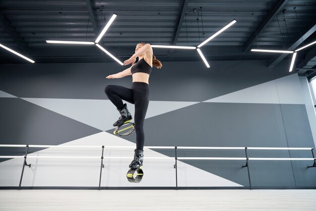 Smiling female teen practicing kangoo jumps indoors