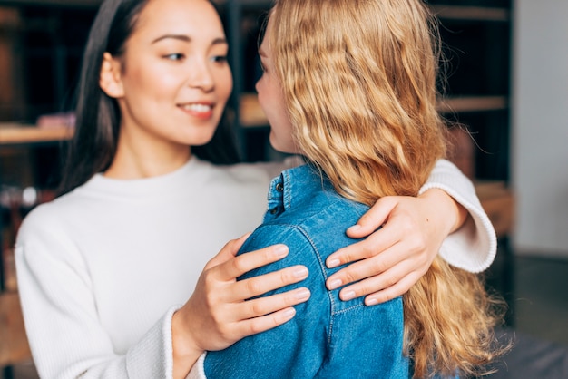 Free photo smiling females embracing at home