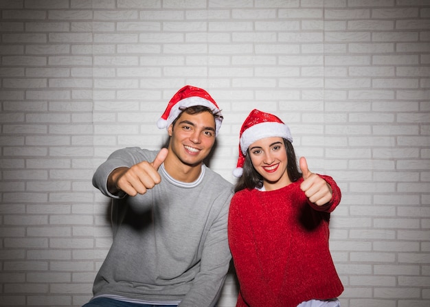 Smiling festive couple showing thumbs up