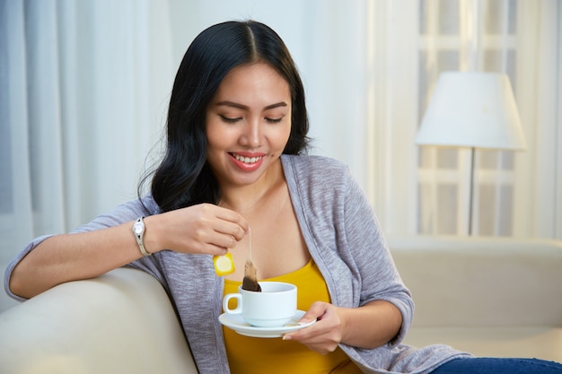 Smiling Filipino female brewing tea on couch