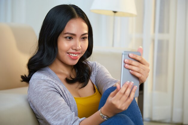 Smiling Filipino female taking selfie at home