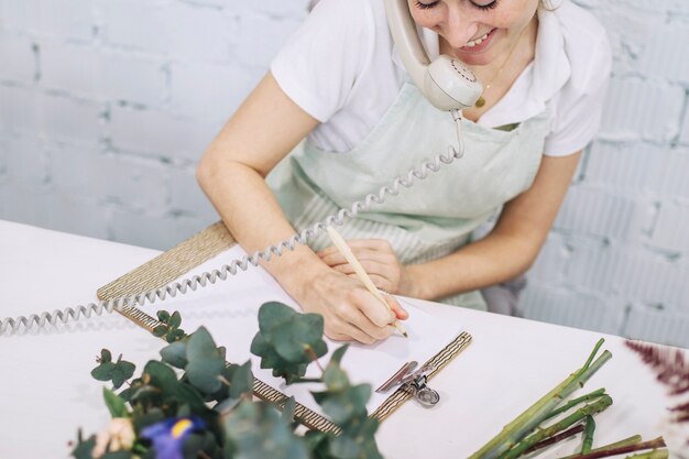 Smiling florist making notes during phone conversation